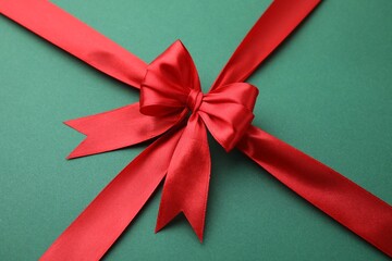 Red satin ribbon with bow on green background