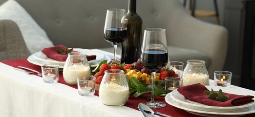 Stylish table setting with burning candles and wine indoors. Romantic dinner