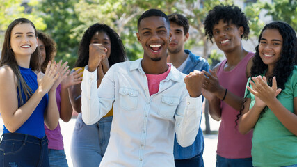 Successful cheering african american young adult with group of applauding people