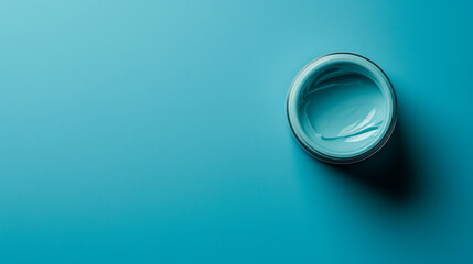 A blank cosmetic cream jar on the right side of a solid blue background with copyspace on the left