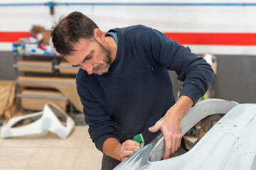 Focused Mechanic Sanding Car Bumper for Restoration