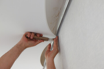 A man attaches the stretch ceiling to the profile.