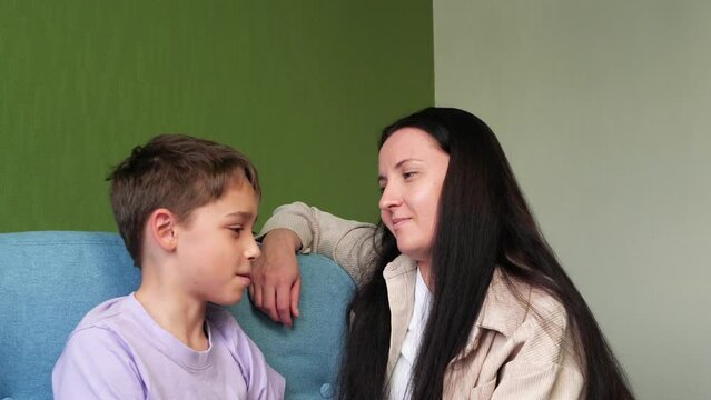  Happy family, mother and son. Mother talks to her child sitting in the room. Mother and son relationship. 