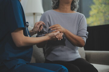 Female caregiver doing regular check-up of senior woman in her home.