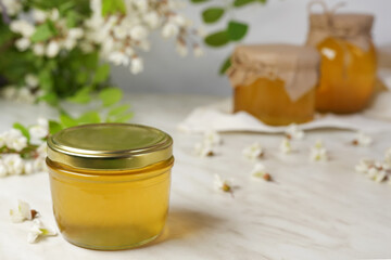 Acacia honey in jar on wooden background. Spring mood. Side view. Space for text. 