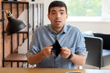 Upset young man with empty wallet in office