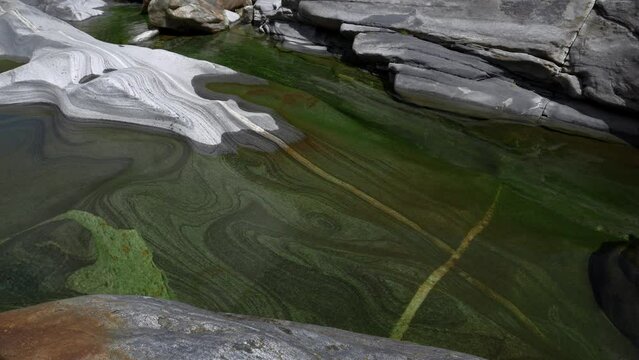 Crystal clear blue water flows through the old stones in the Verzasca valley. The stones have been ground down over centuries. pure nature