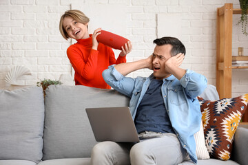 Working young man stressed of his noisy little son with speaker at home