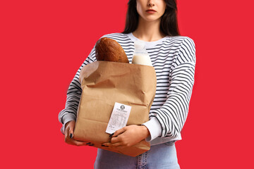 Young woman with shopping bag and receipt on red background, closeup. Price rise concept