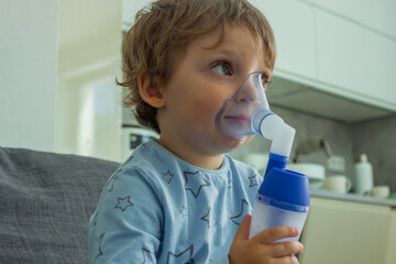 The boy makes inhalations with nebulizer at home, he's got a cold.