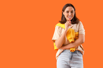 Young woman smoking electronic cigar on orange background