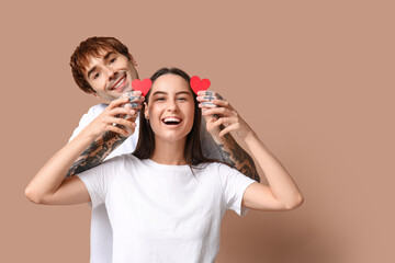 Young couple with paper hearts on beige background