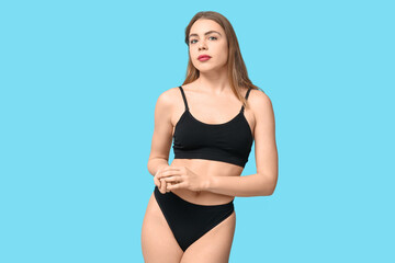 Sexy young woman in black cotton underwear on blue background