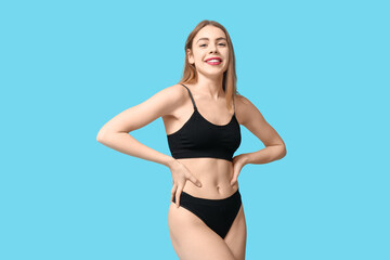 Fototapeta premium Sexy young woman in black cotton underwear on blue background