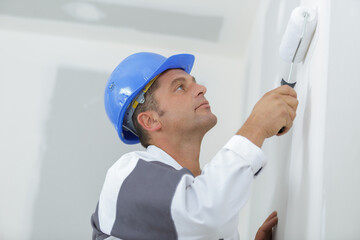 young worker painting wall in room