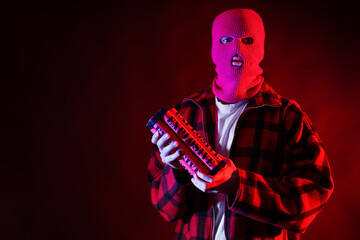 Handsome young man in balaclava with bomb on black background
