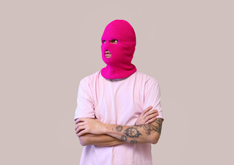 Handsome young man in balaclava on beige background