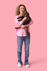 Mature woman with cute cat on pink background