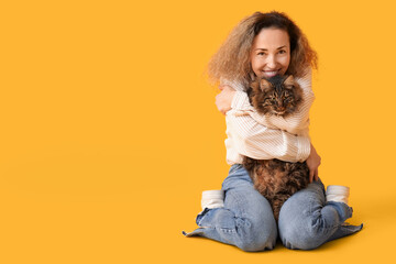 Mature woman with cute cat on yellow background