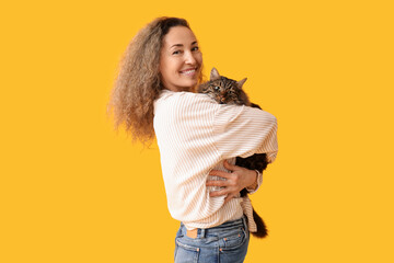 Mature woman with cute cat on yellow background