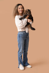 Beautiful mature woman with cute cat on brown background