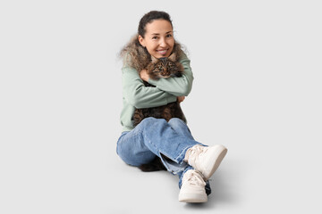 Mature woman with cute cat sitting on grey background