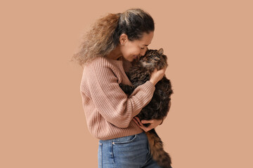 Beautiful mature woman with cute cat on brown background