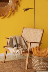 Interior of living room with armchair and basket near yellow wall