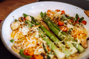 fried asparagus with cheese and egg in a frying pan