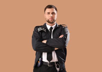 Male police officer with crossed arms on beige background