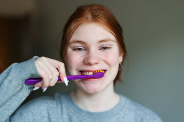 Young woman brushing teeth with charcoal toothpaste