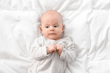 Cute little baby lying on white sheets, top view