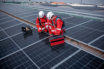 Engineers walking and holding box on factory roof inspection survey and check solar cell panel...