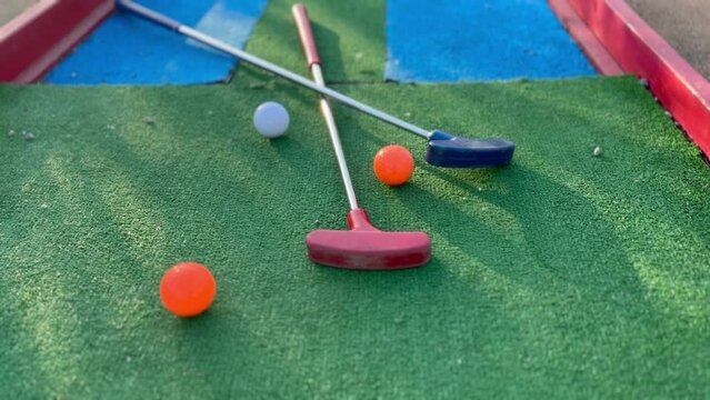 colorful golf putters with golf balls on synthetic grass
