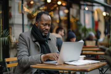 Serious African American businessman working on laptop at outdoor café
