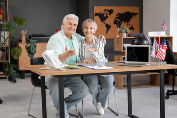 Happy mature couple hugging at table in travel agency