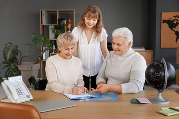 Obraz premium Mature couple with travel agent filling out visa application in office