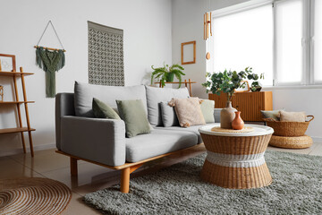 Interior of light living room with wind chime, sofa and plants