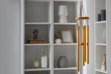 Golden wind chime hanging in light bedroom, closeup