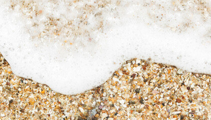 Sea wave over sand close up.  White foam wave sandy seashore top view.