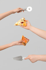 Many hands holding pizza slices, spatula and pizza cutter on white background