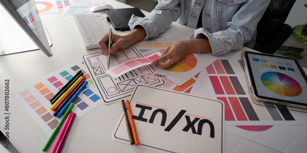 Poster stylish woman ux designer using digital tablet and computer planning new website wireframe at creati