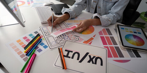 Stylish woman Ux designer using digital tablet and computer planning new website wireframe at...
