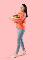 Young woman with unhealthy food on pink background. Overeating concept