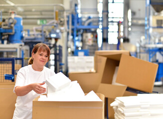 woman works in the shipping department of a company and packs styrofoam components into packages for the customer