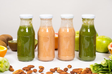 Different vegetable and fruit smoothies in glass bottles on white background