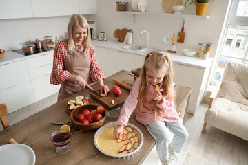 Little girl with her mother cooking apple pie in kitchen