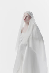 Young, calm woman shrouded in gossamer white fabric, creating ghostly yet angelic appearance...