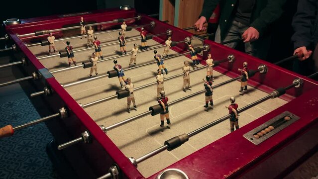 People playing in table football or kicker with miniature players. Table football game. Employees playing table soccer indoor-game in the office during break time.