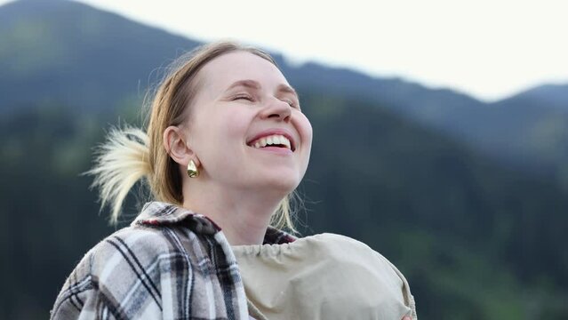 A young mother in nature enjoys life and fresh air, hugging a sleeping baby in an ergo backpack sling. close-up